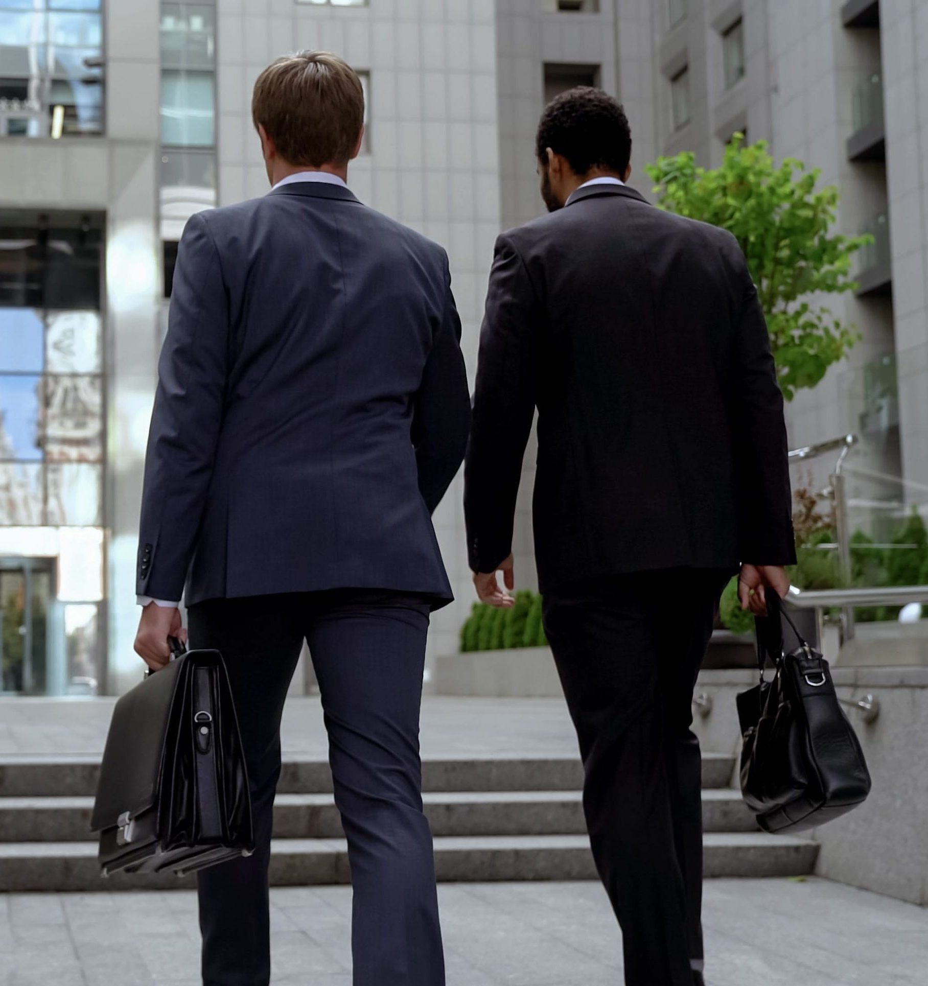 Lawyers approaching office building dressed in suits carrying briefcases.